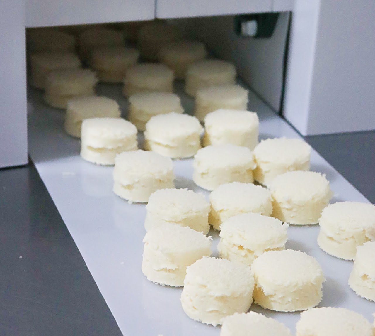 Pão de queijo saindo da Dosadora G13 sobre a esteira